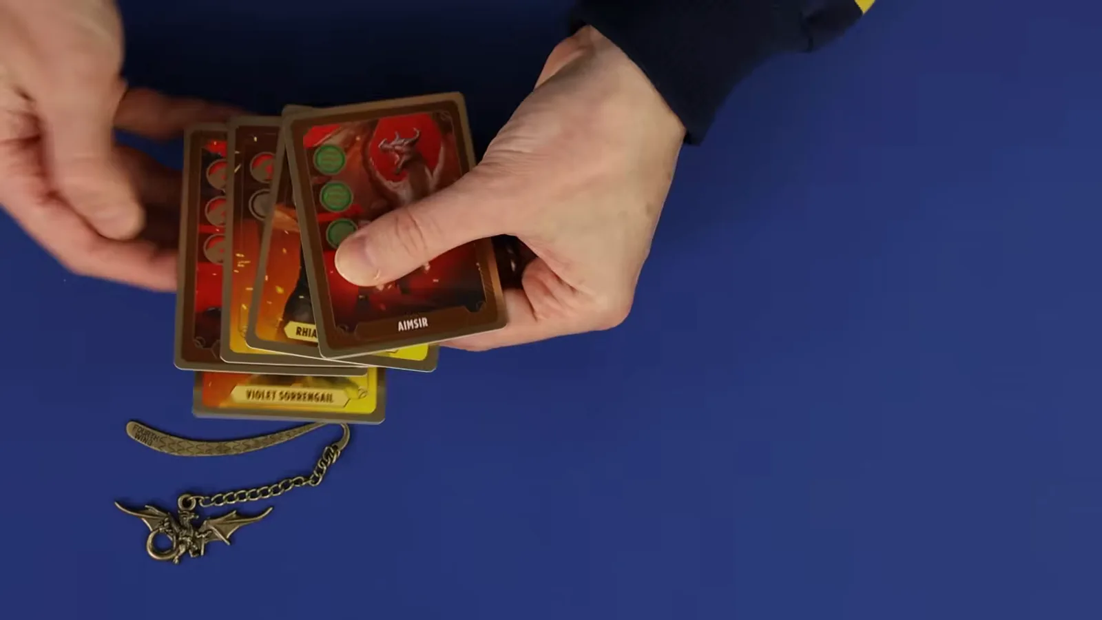 La mano de cartas de aliados de Rise of the Wingleader se despliega sobre la mesa, con las cartas de Andarna y Violet Sorrengail visibles junto al marcapáginas de dragón de metal.